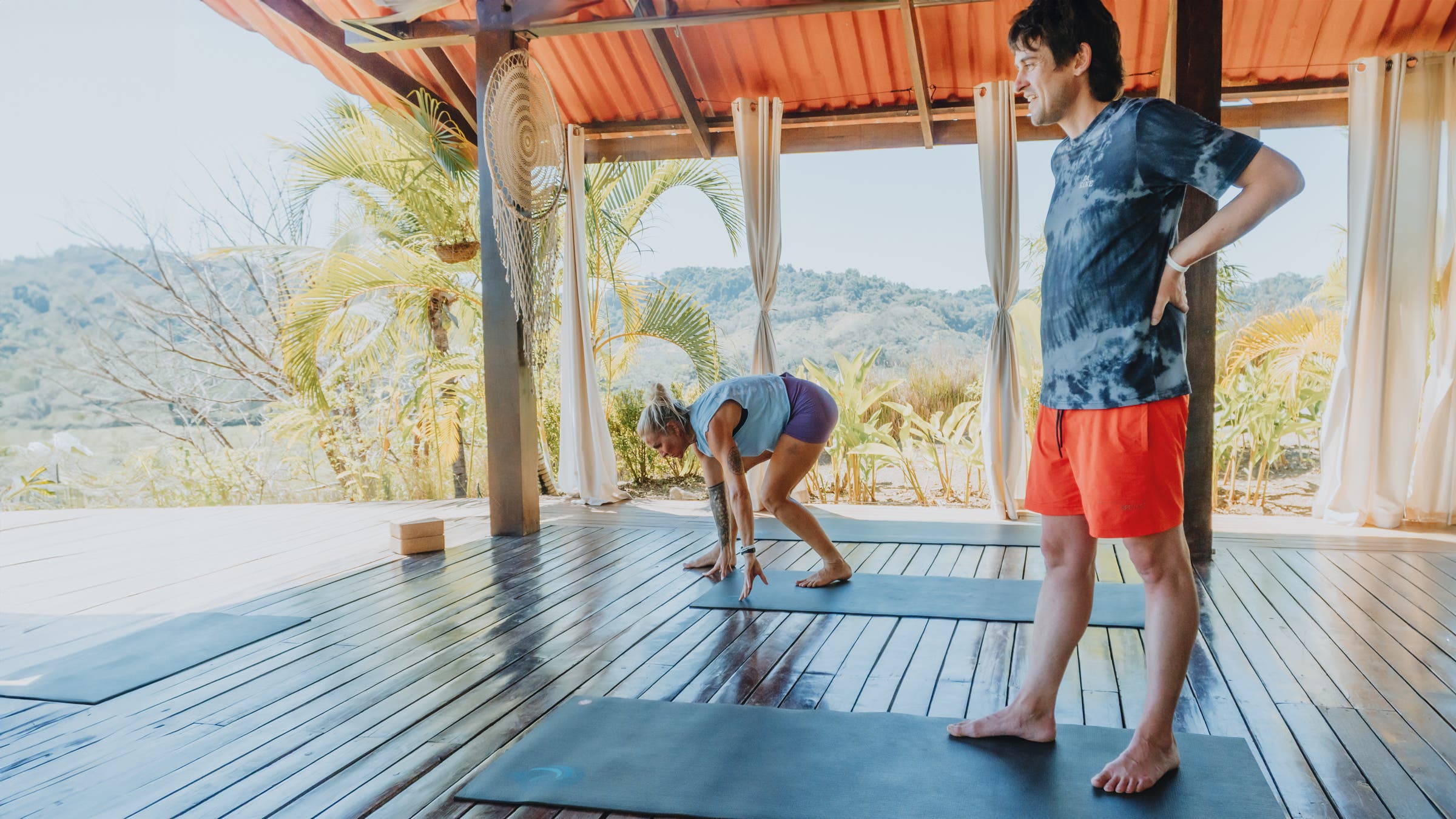 Author Joe Jackson wearing SPC/LST Solstice Short performance swim trunks while doing yoga on deck overlooking tropical mountains